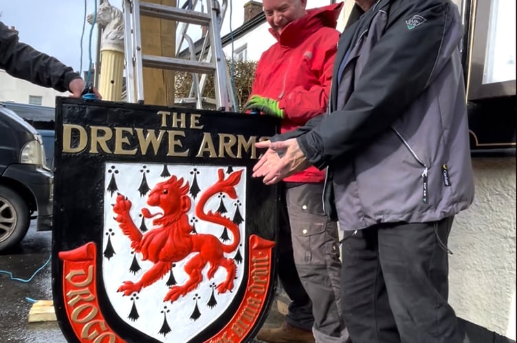 The Drewe Arms sign being raised and put back into pride of place.
