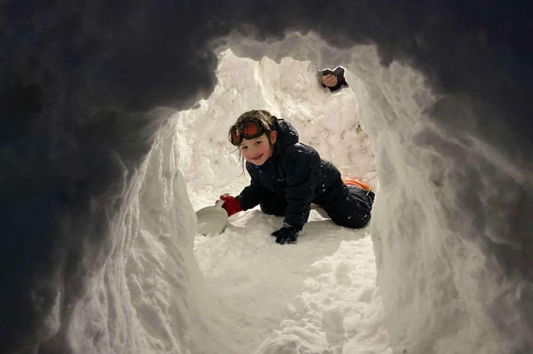 A little girl with the igloo she and a group  of children made at Princetown